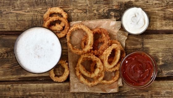 onion rings on board with dipping sauces